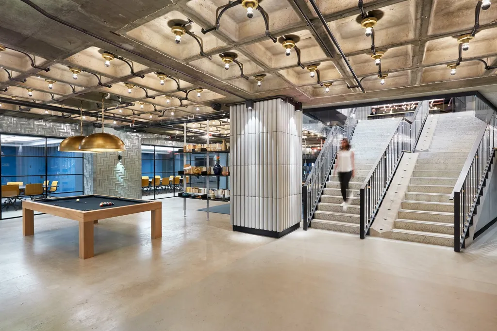 A private lounge with a pool table and a person descending a staircase.
