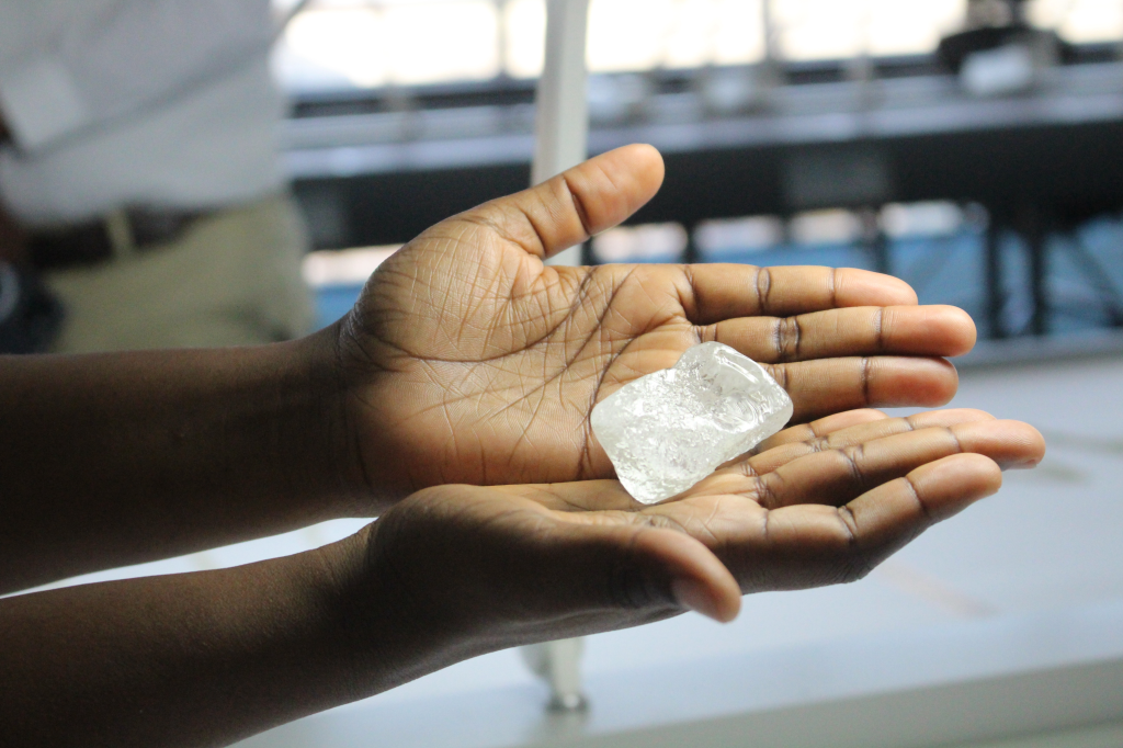 Hands holding a raw diamond.