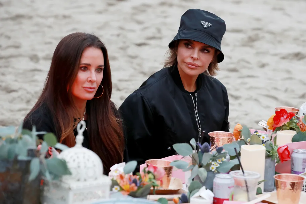 Kyle Richards and Lisa Rinna at a table on the beach.
