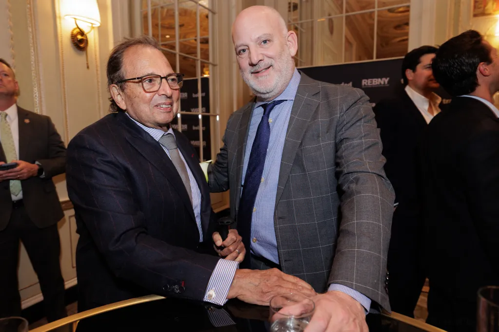 Two men in suits smiling at the REBNY 130th Annual event.