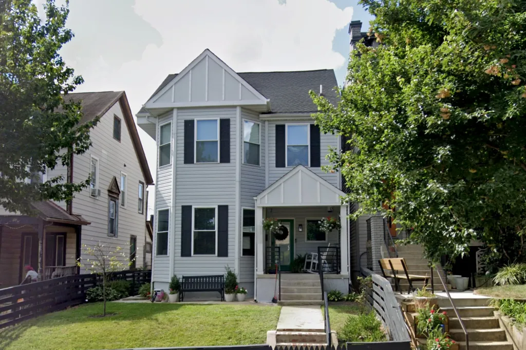 The Washington D.C. home of Rep. Eric Swalwell, a light gray house with black window shutters and a front porch, framed by green trees.