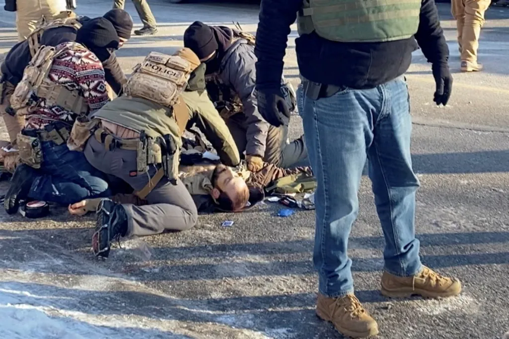Law enforcement officers kneel next to the body of a man fatally shot by federal agents in Minneapolis.