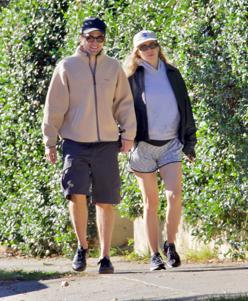 Robert Pattinson and Suki Waterhouse walking outside, with Suki appearing to have a baby bump.