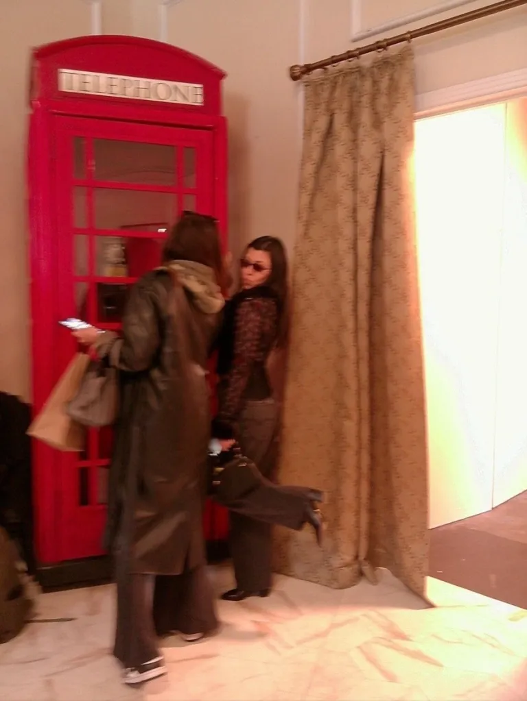 Kourtney Kardashian and Penelope Disick posing near a red telephone booth.