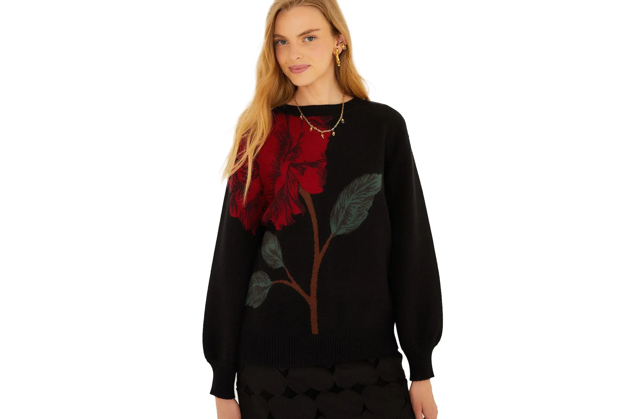 A woman wearing a black sweater with a large red rose design, green leaves, and brown stem.