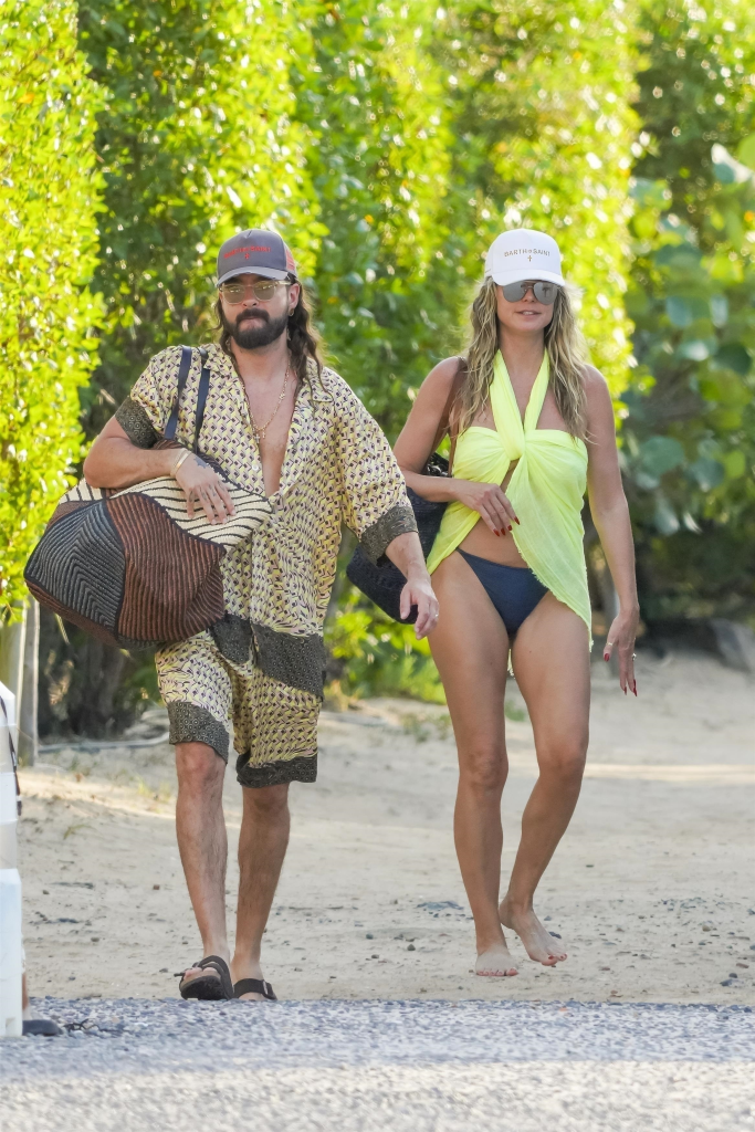 Heidi Klum and Tom Kaulitz walking on a beach path.