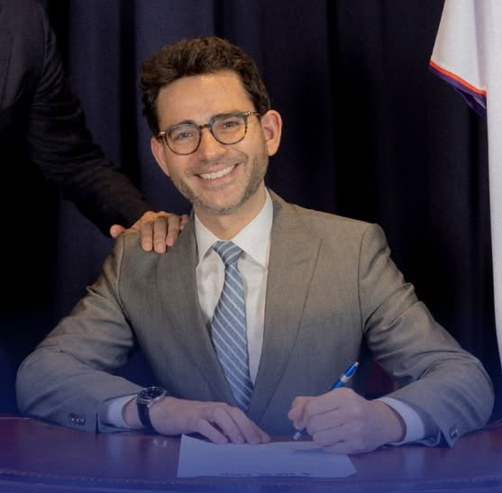 Samuel Levine signing a document.