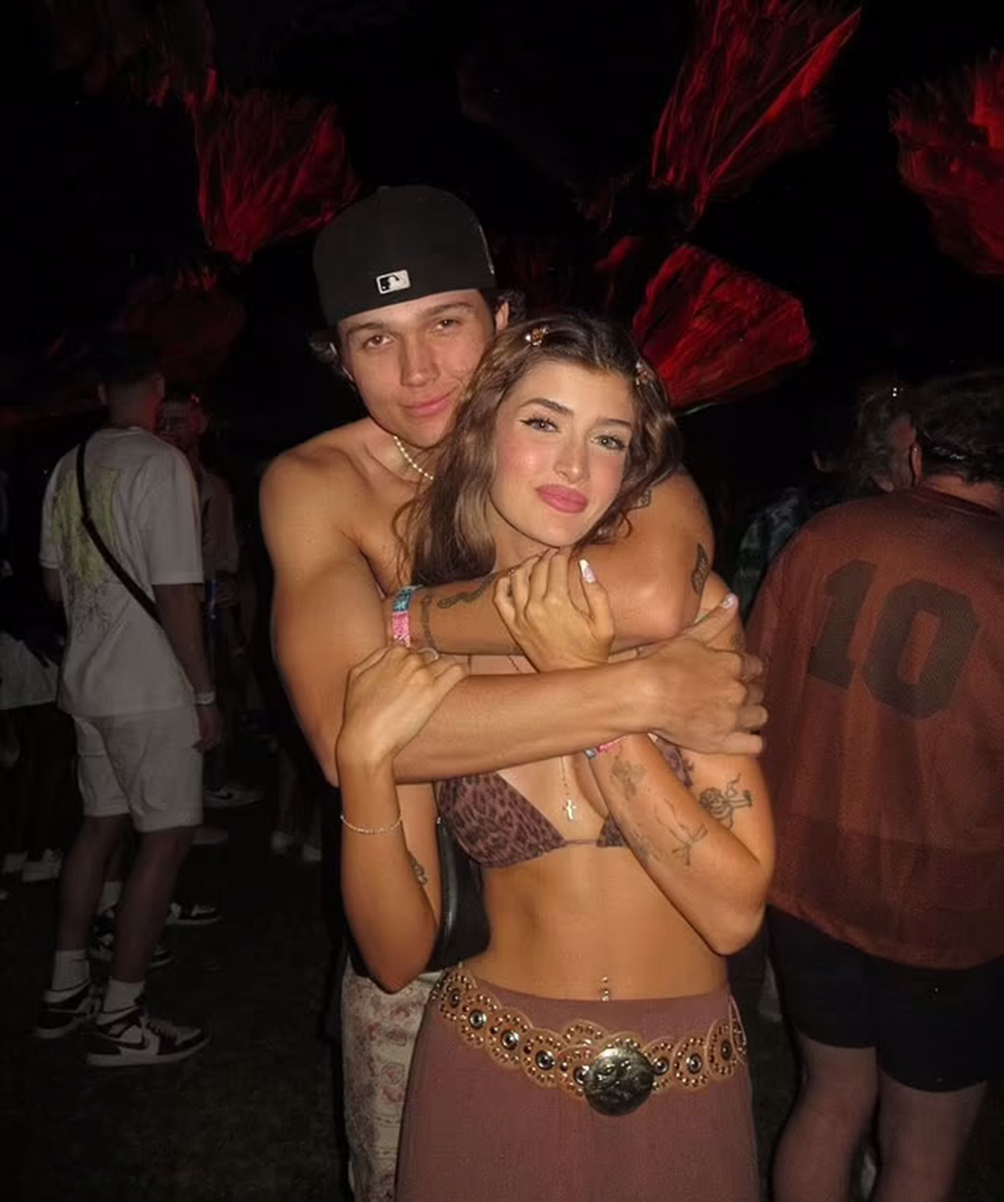 Sami Sheen and Aidden David embracing at a dark event with red lighting.