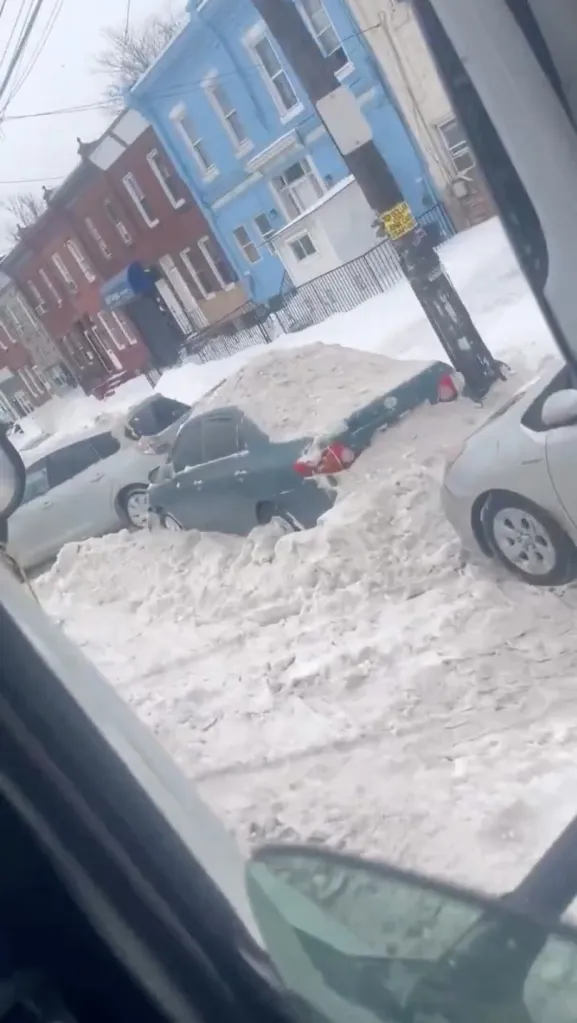 Snow plow pushing snow onto parked cars in Kensington.