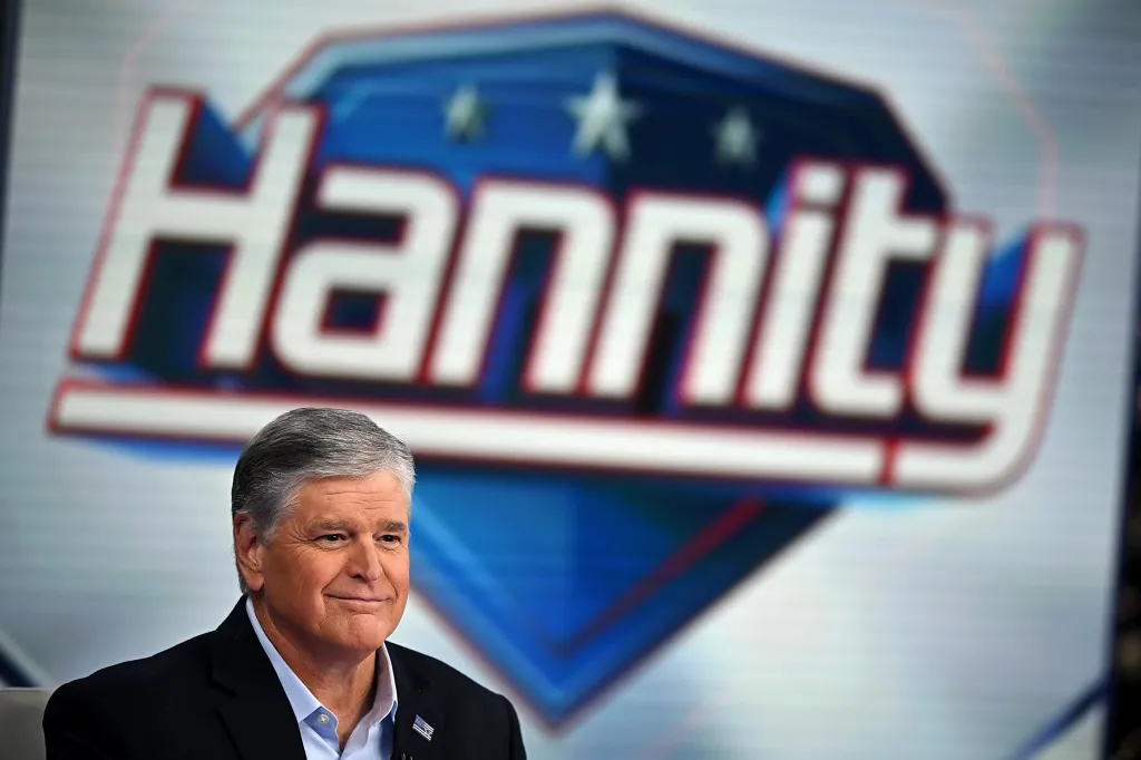 Sean Hannity smiling in front of a blurred 