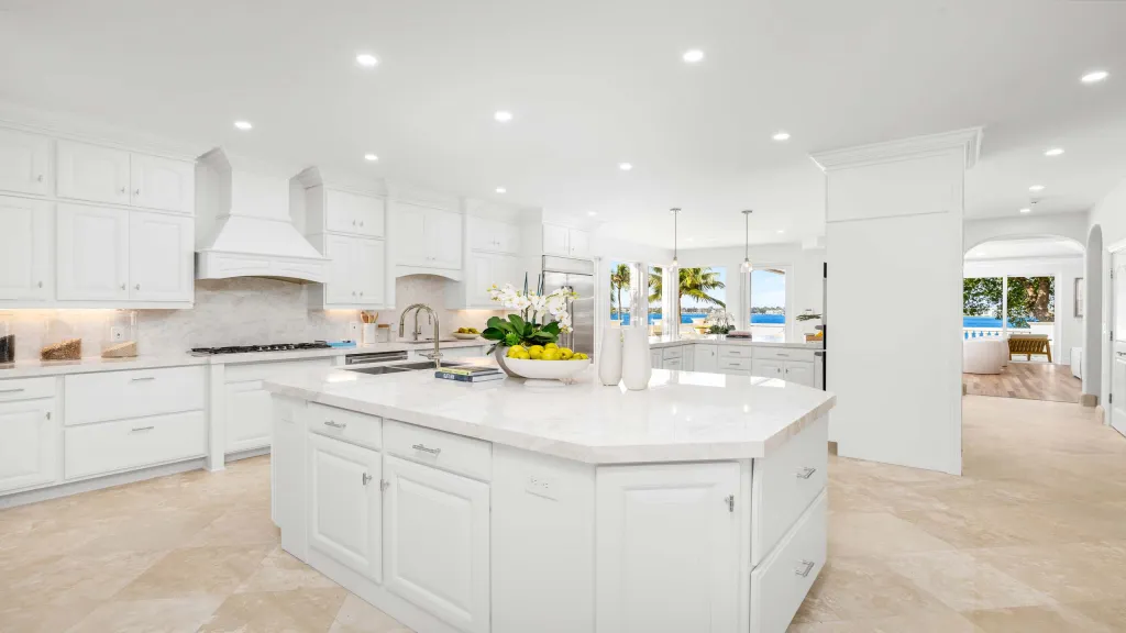 White kitchen with large island and view of the water.