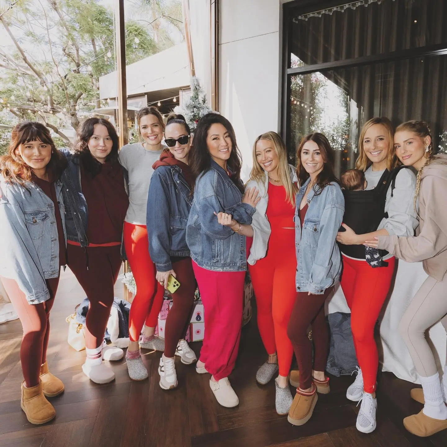 A group of nine women wearing athletic wear, some in red leggings, pose together.