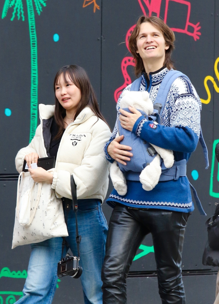 Ansel Elgort carrying a baby in a papoose with his partner.