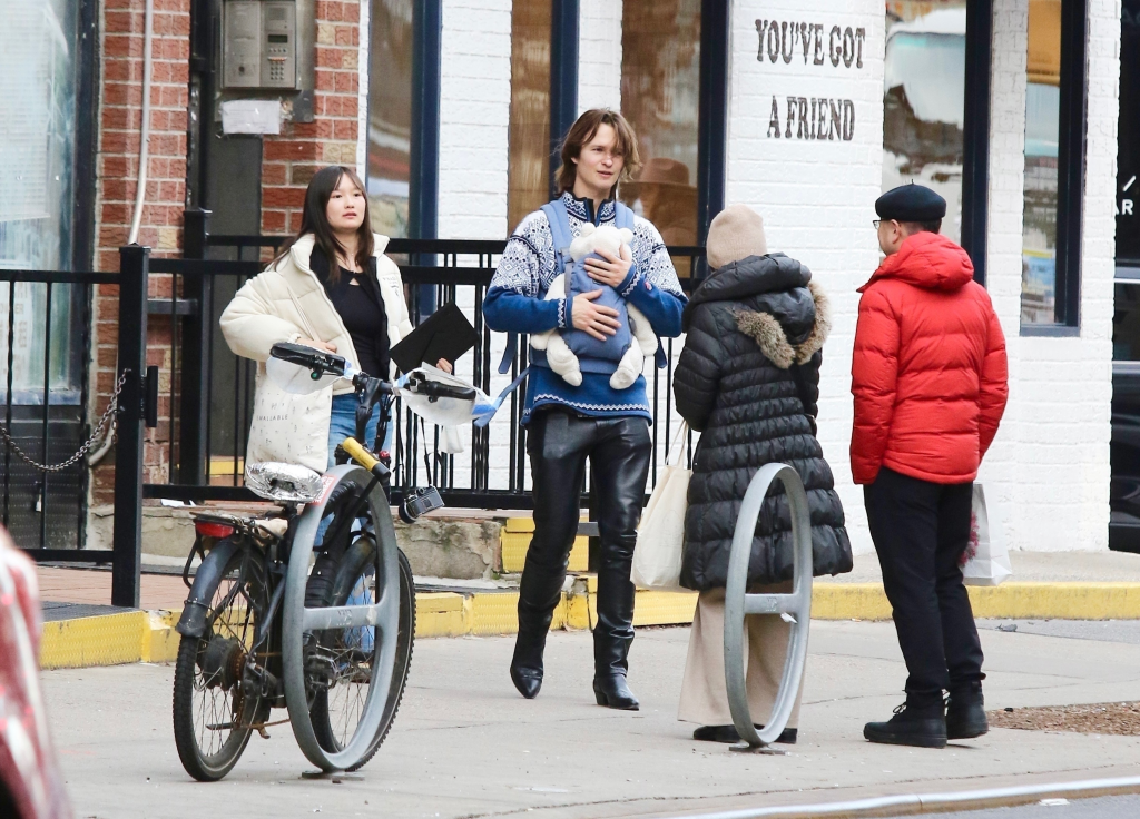 Ansel Elgort carrying a baby in a papoose, with his partner and her parents, in New York City.