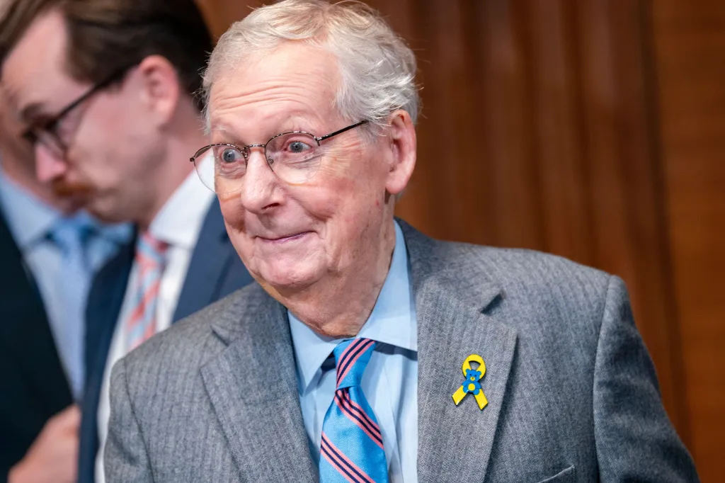 Senator Mitch McConnell at a hearing, wearing a blue and yellow ribbon pin with a teddy bear, symbolizing Ukrainian children.