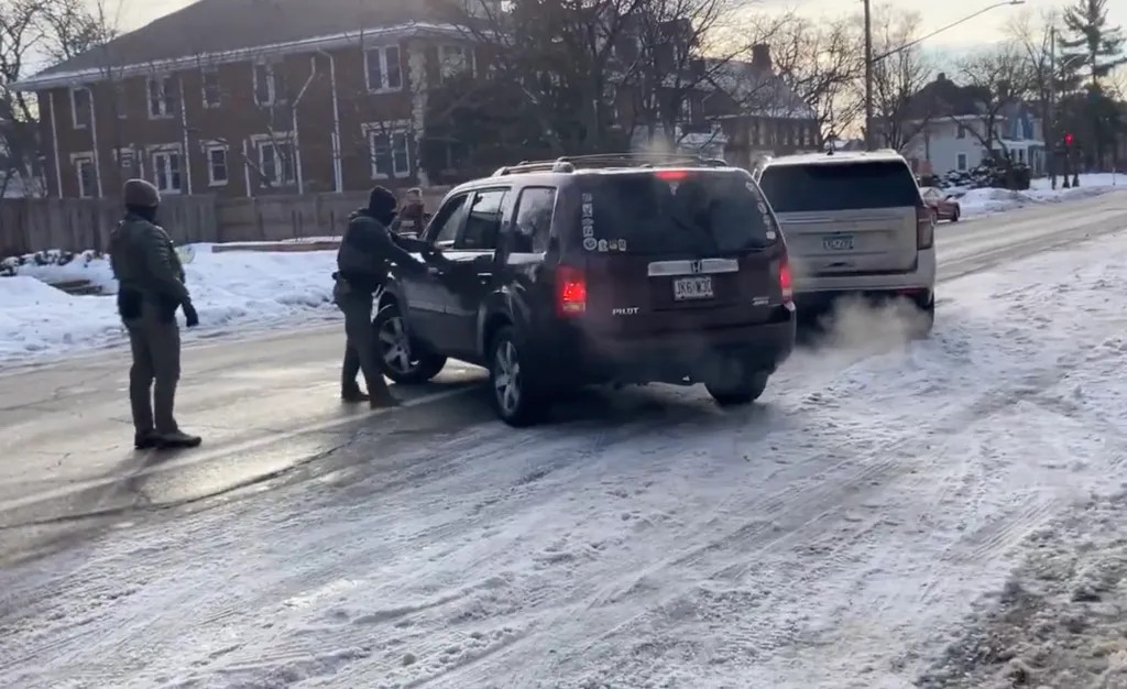 Federal Agents attempting to apprehend an individual in a maroon SUV on a snowy street.