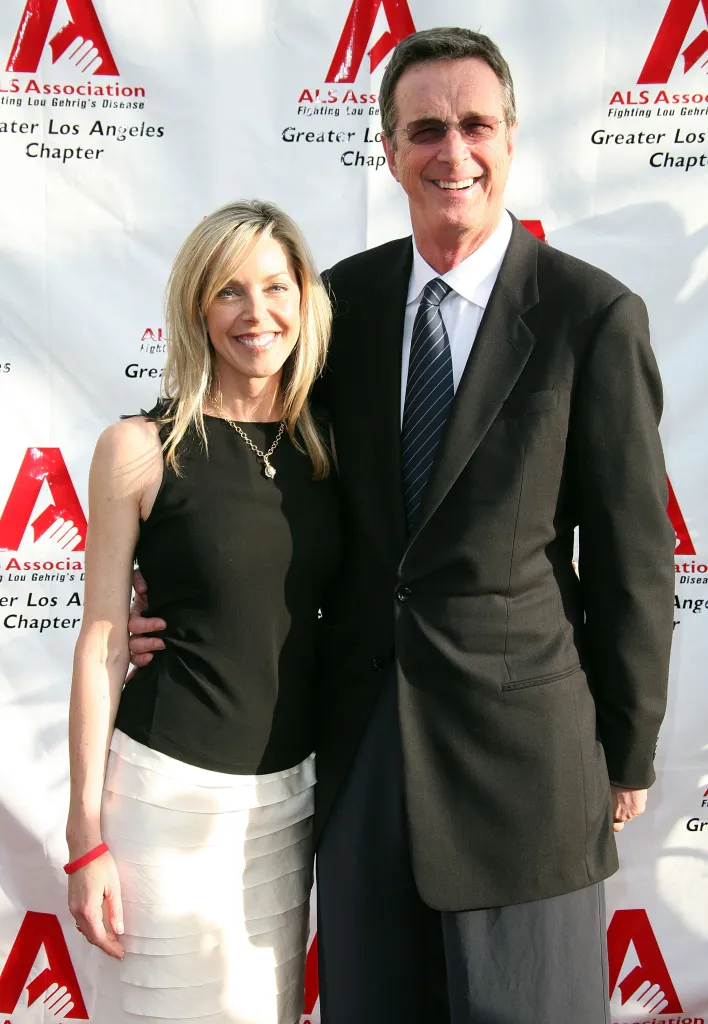 Sherri Crichton, in a black top and white skirt, and author Michael Crichton, in a black suit and striped tie, smiling at an ALS Association event.