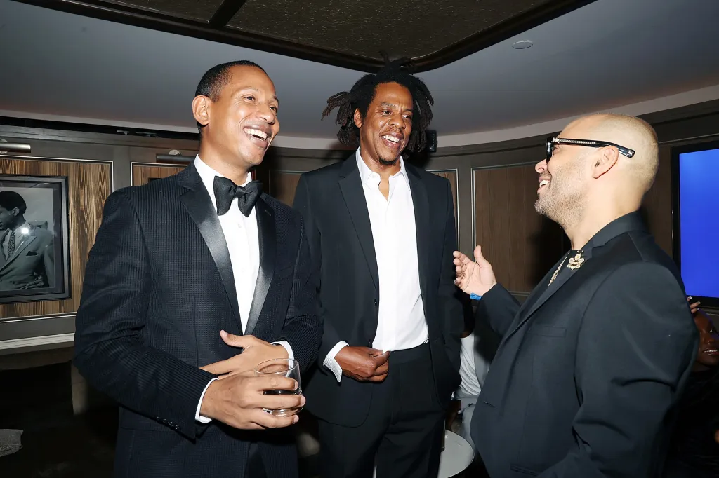 Shyne, Jay-Z, and Richie Akiva smiling at an event.