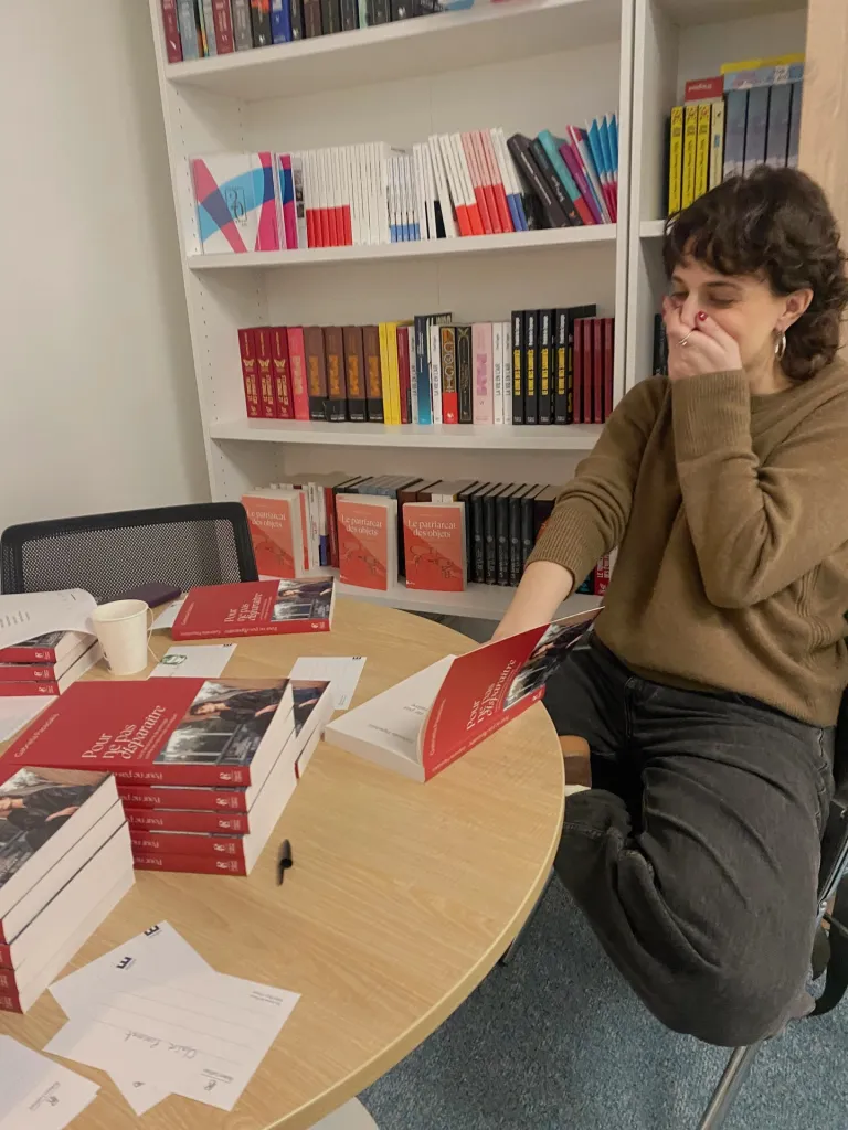 A woman signing copies of her book 