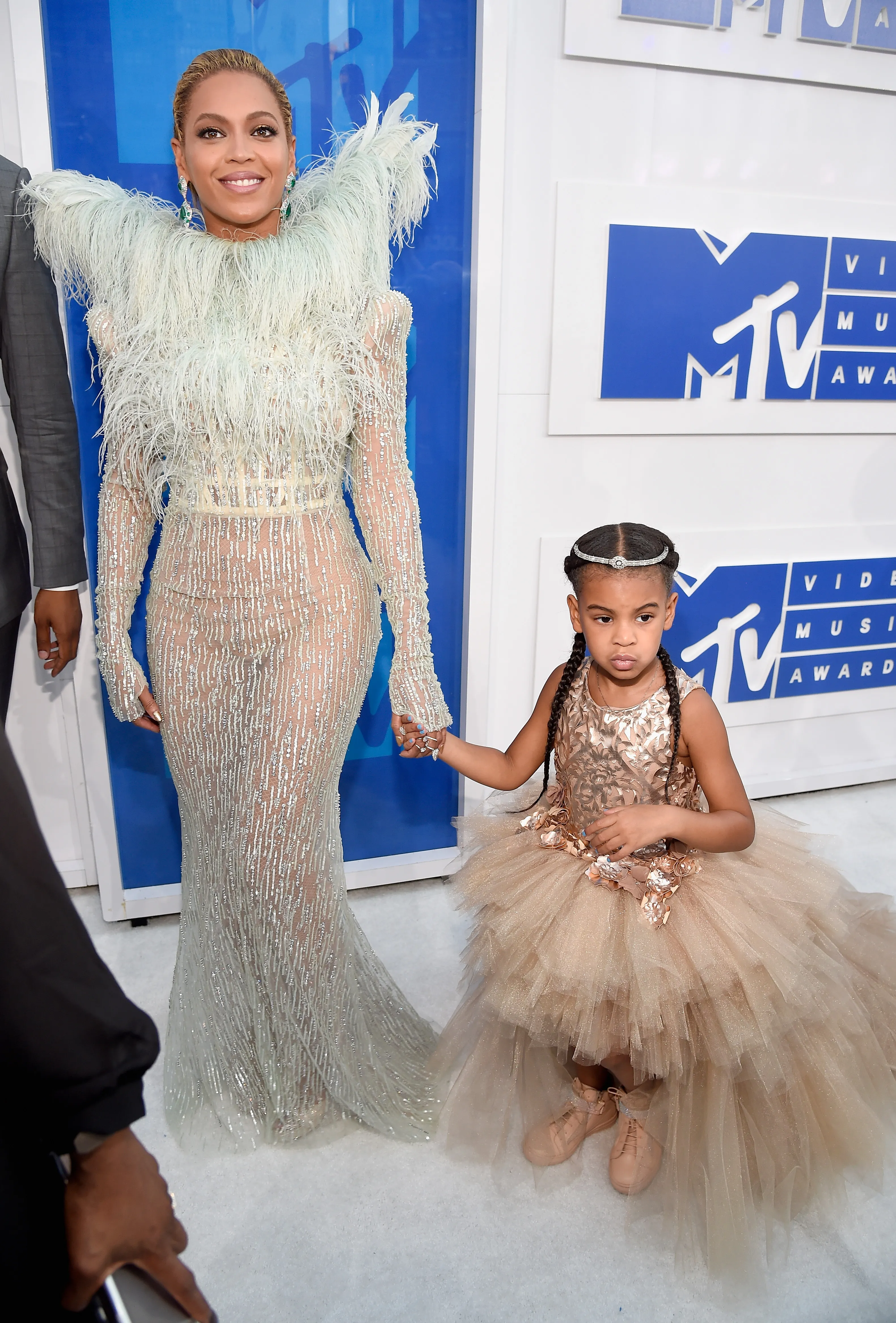 Beyoncé in a feathered dress holding hands with her daughter Blue Ivy in a tulle gown at the 2016 MTV Video Music Awards.
