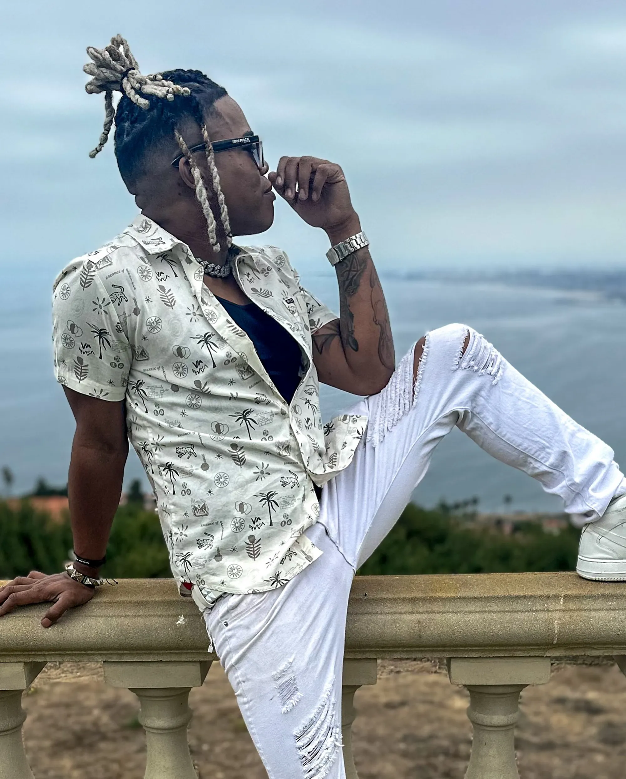 Brian King sitting on a stone railing, looking out at the ocean.