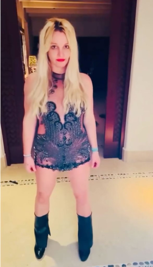 Britney Spears in a sparkly black mini-dress and black boots.