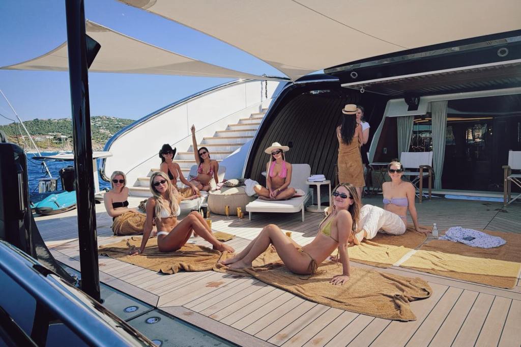A group of women in bikinis lounging on towels on the deck of a yacht.