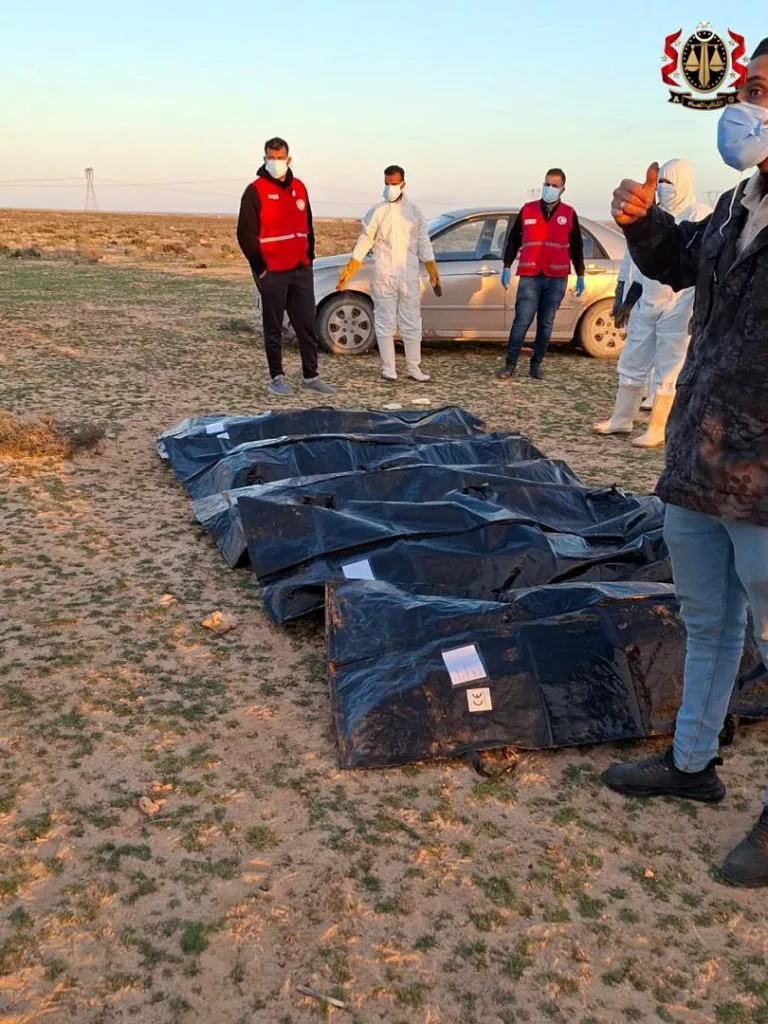 Security personnel and Red Crescent volunteers around body bags on the ground near Ajdabiya, Libya.