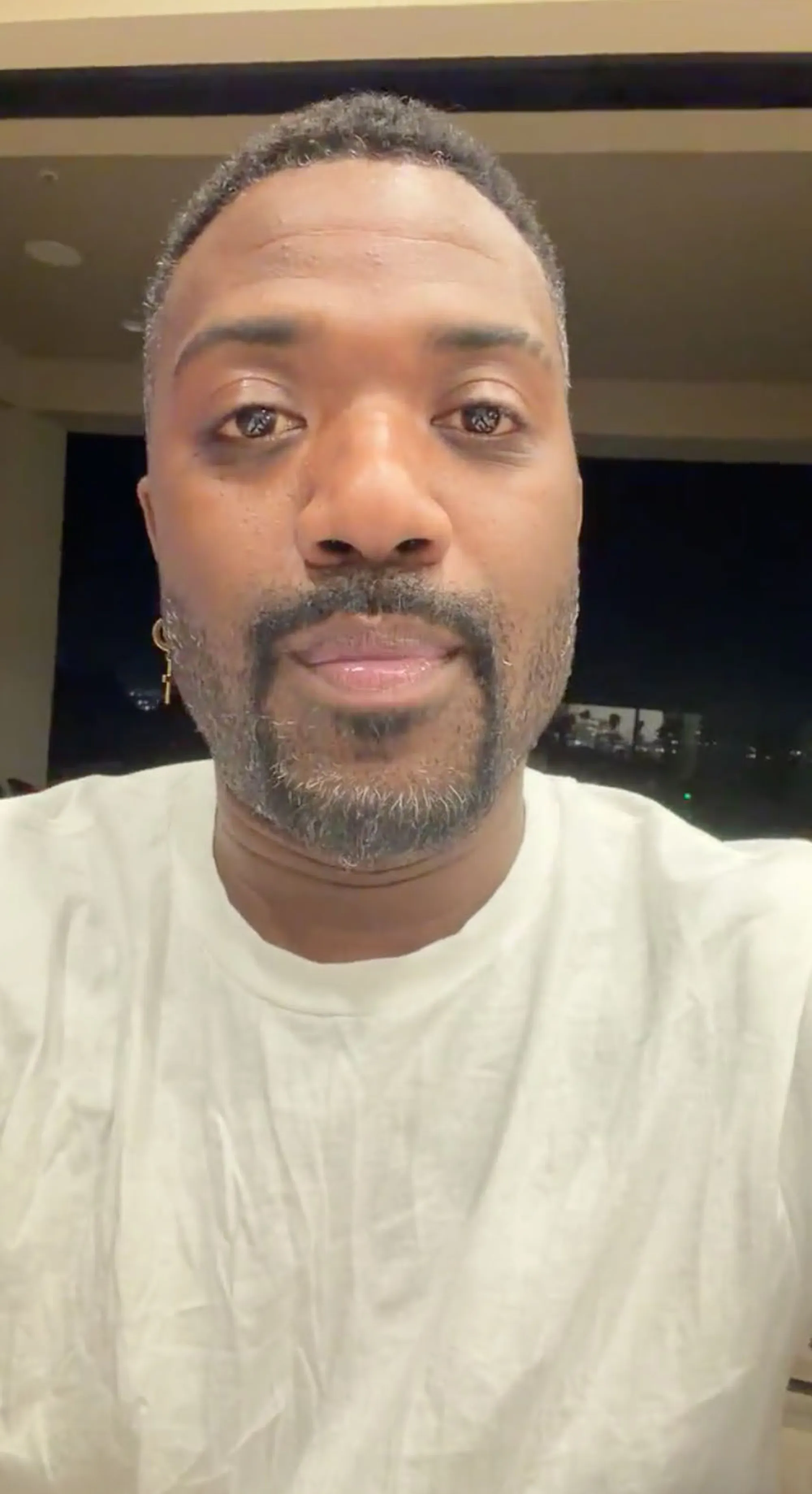 Ray J with a beard and cross earring, wearing a white t-shirt.
