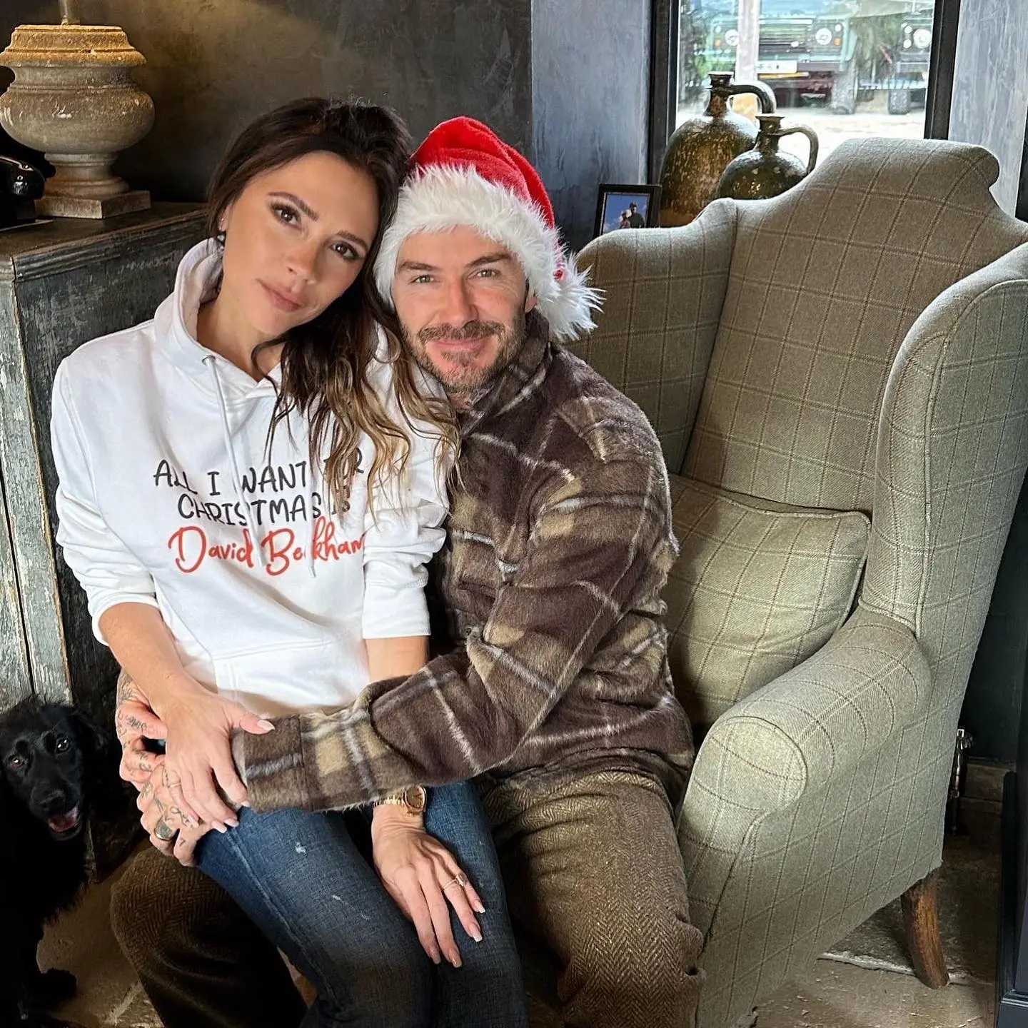Victoria and David Beckham posing together, with David wearing a Santa hat.