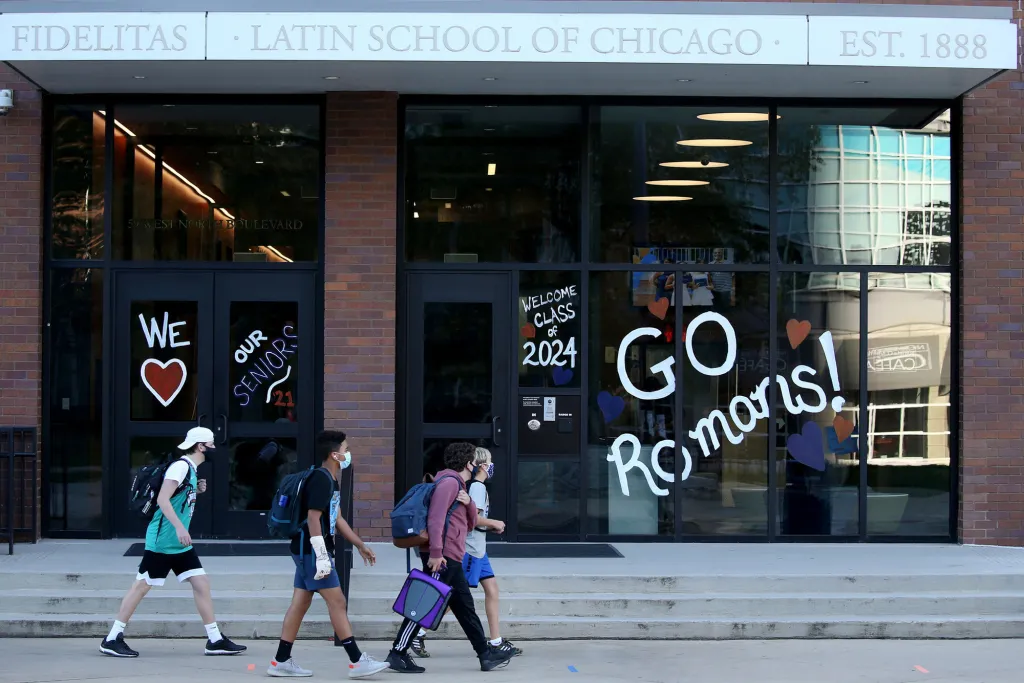 Students in masks walking past the Latin School of Chicago building.