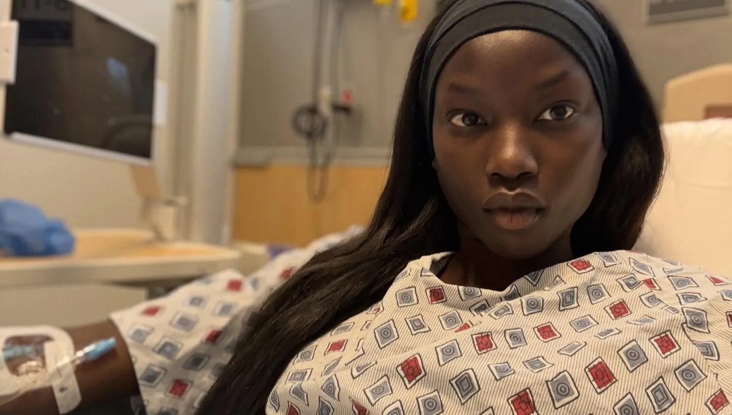 Anok Yai in a hospital bed with an IV in her arm.