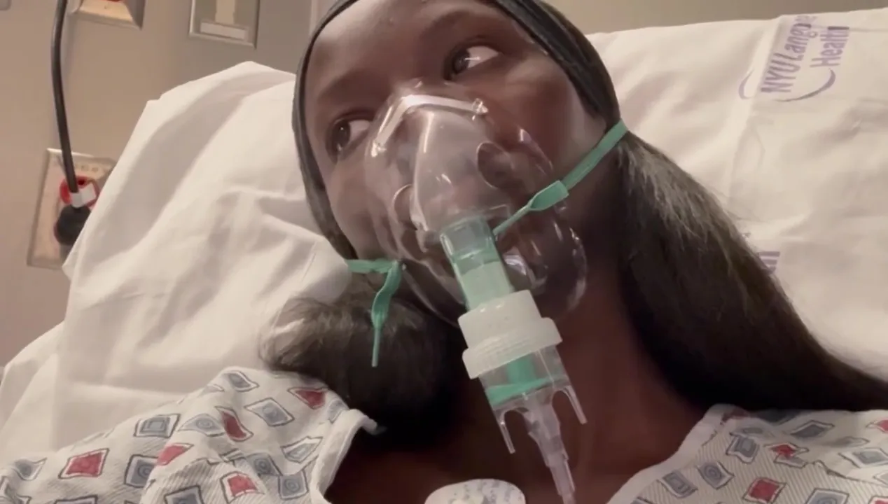 Anok Yai in a hospital bed with an oxygen mask on.