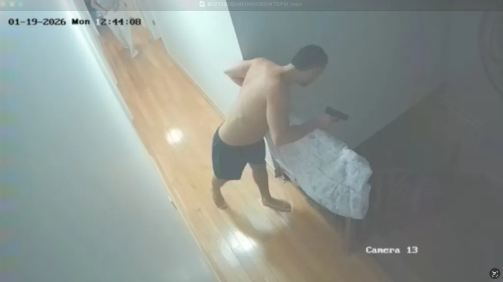Surveillance footage of Moshe Borukh holding his gun during a home invasion.