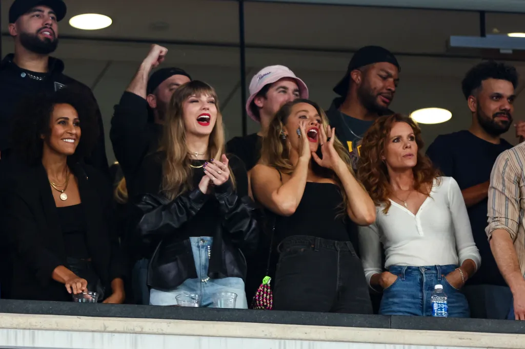 Taylor Swift and Blake Lively cheer from the stands during an NFL game.
