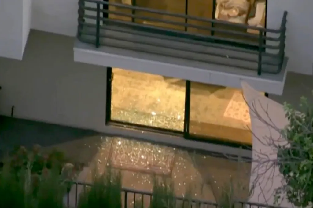 Glass shards litter the ground beneath a broken sliding glass door.