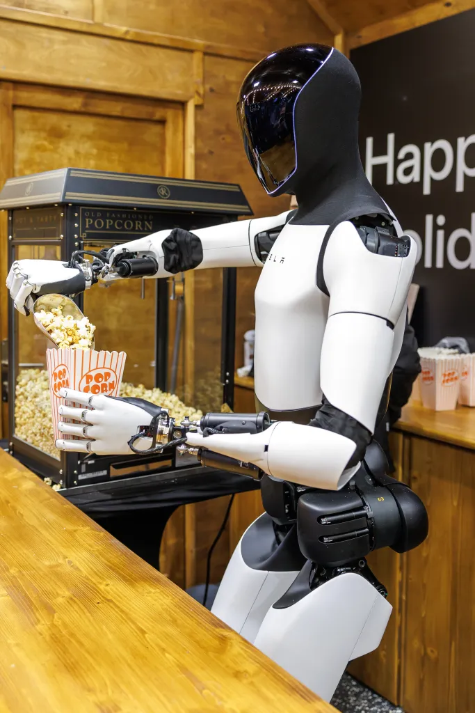 Tesla's humanoid robot Optimus serving popcorn from a machine into a cup.