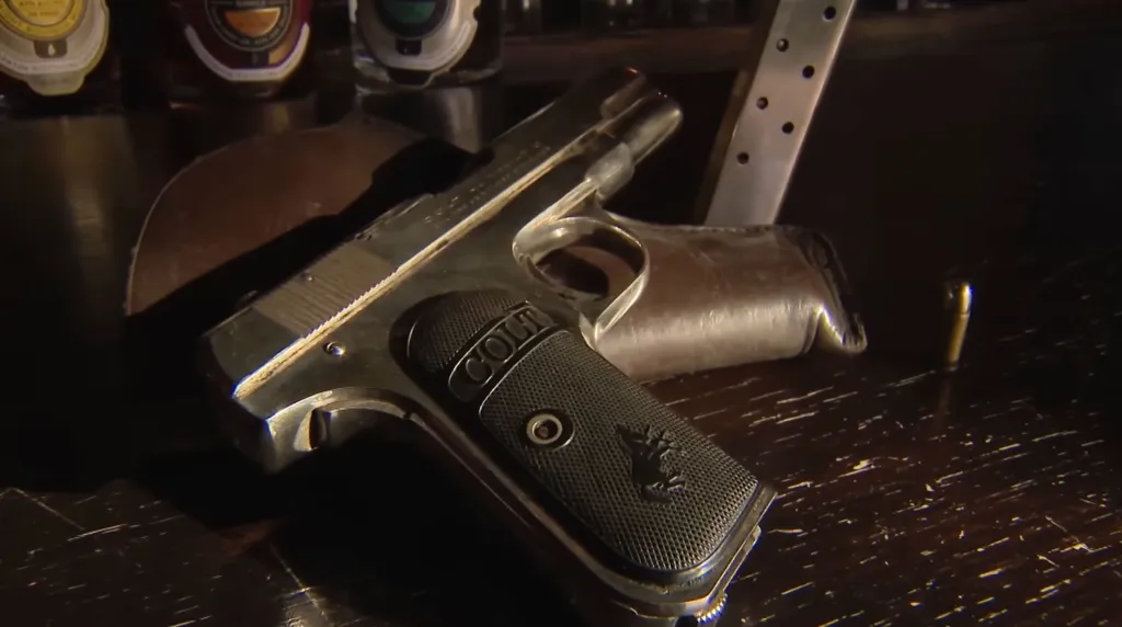A loaded Colt Model 1908 pistol from the 1920s with a magazine and a bullet resting on a table.