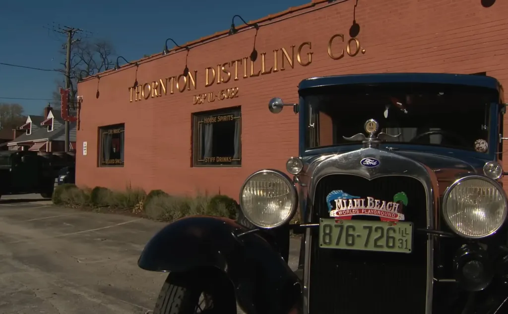 A vintage Ford car parked in front of Thornton Distilling Co.