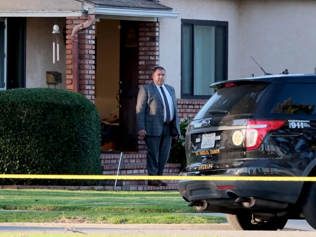 Officials walk out of the home during the investigation into the murder-suicide.