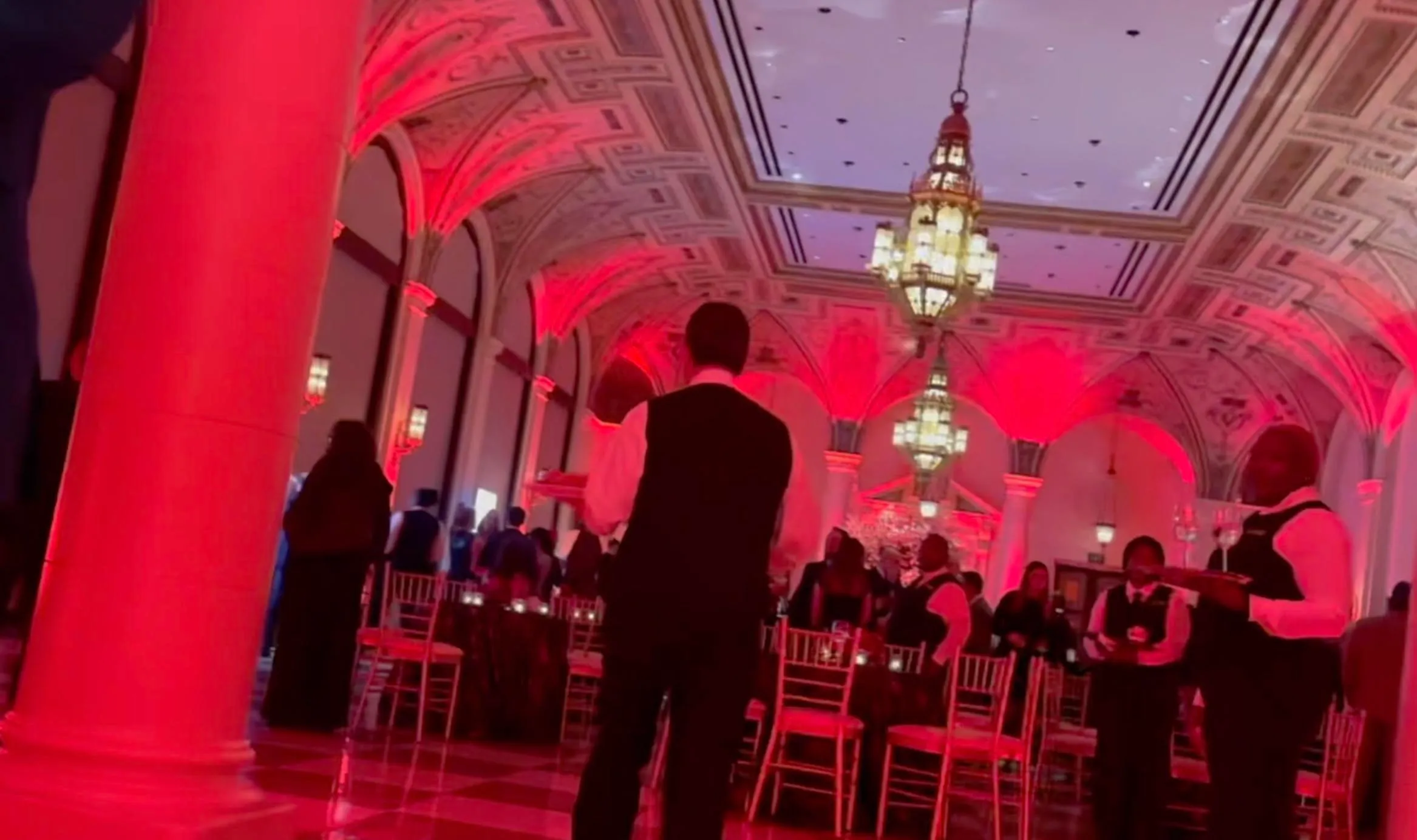 Tiger Woods' birthday party ballroom with guests, waiters, and red lighting.