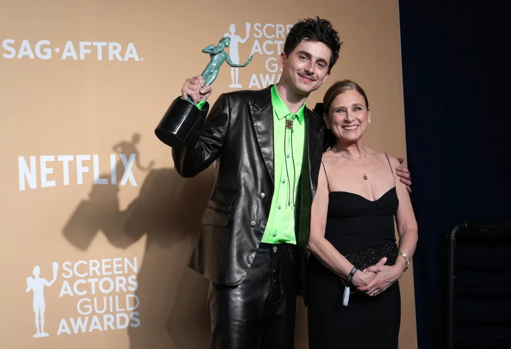Timothée Chalamet and Nicole Flender posing with the Outstanding Performance by a Male Actor in a Leading Role award.