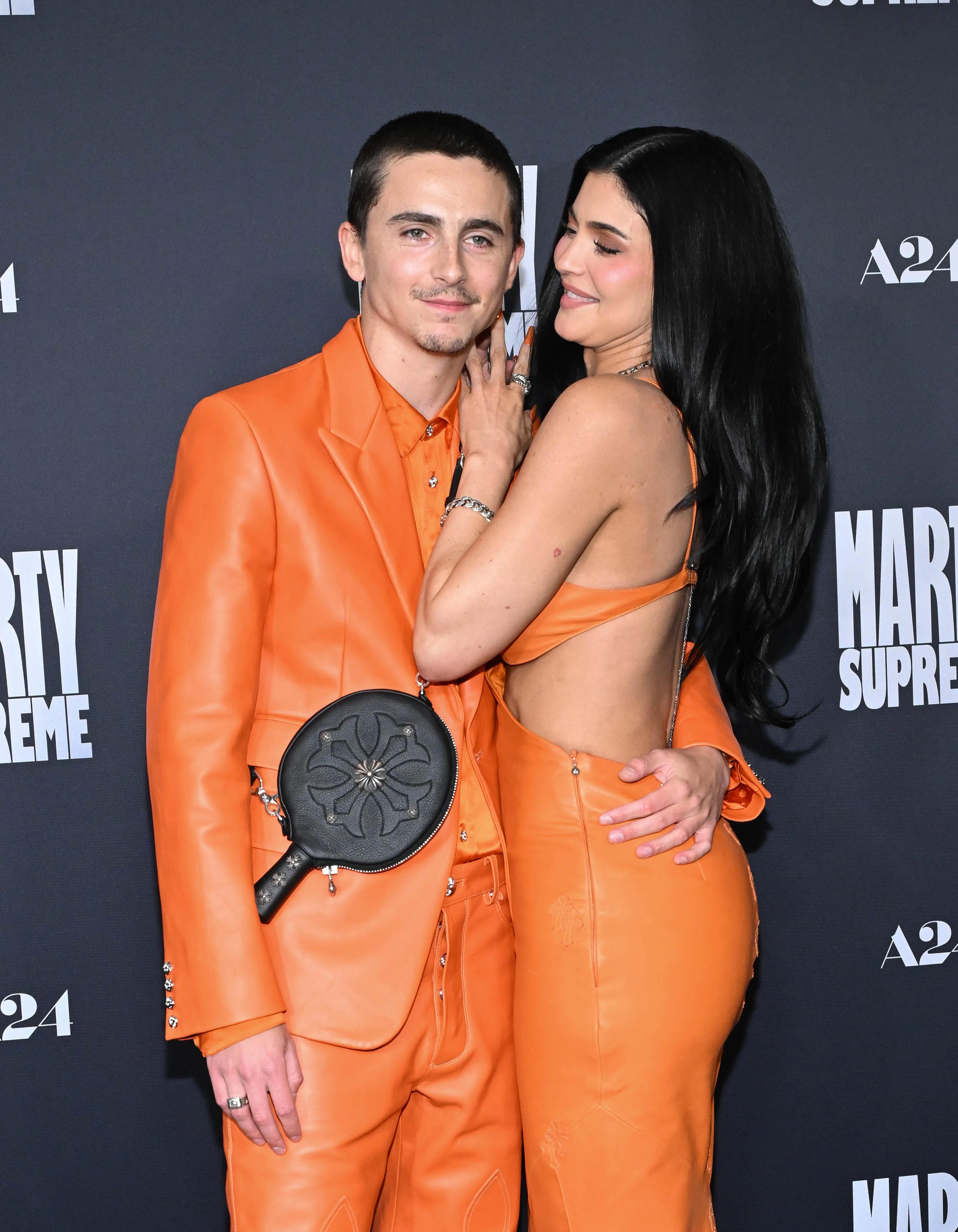 Timothée Chalamet and Kylie Jenner posing in orange outfits at a 