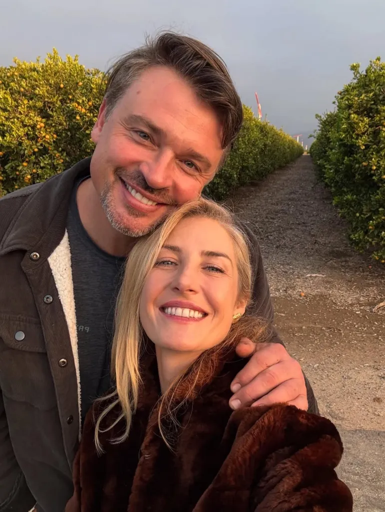 Tom Welling and his wife Jessica Rose Lee smiling, with Tom's arm around her.