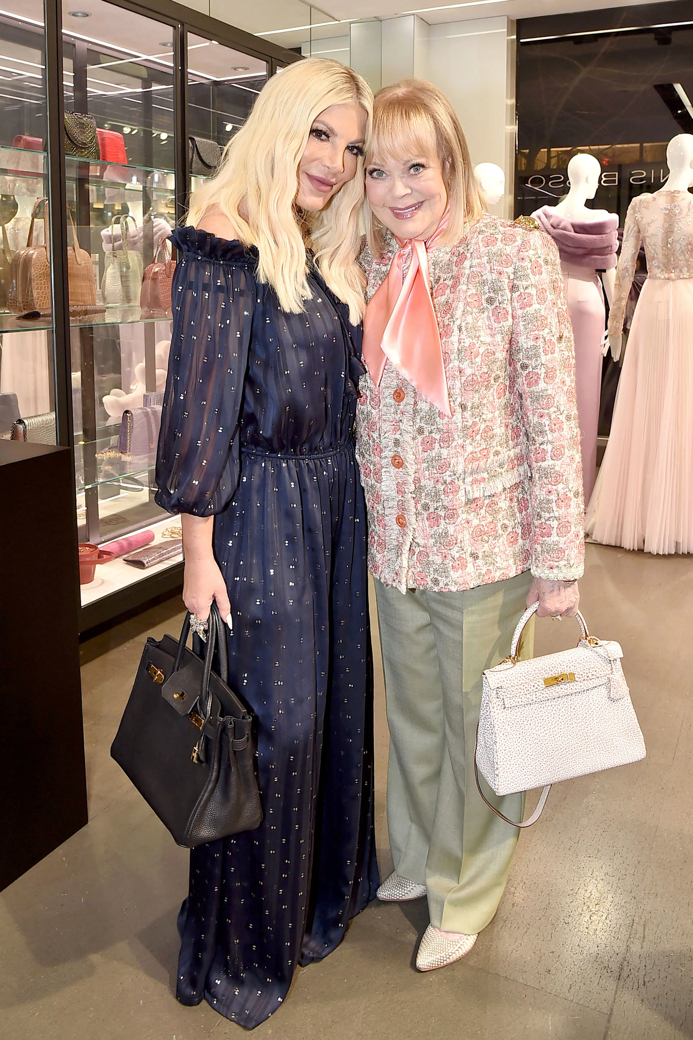 Tori Spelling and Candy Spelling pose together, both holding handbags.