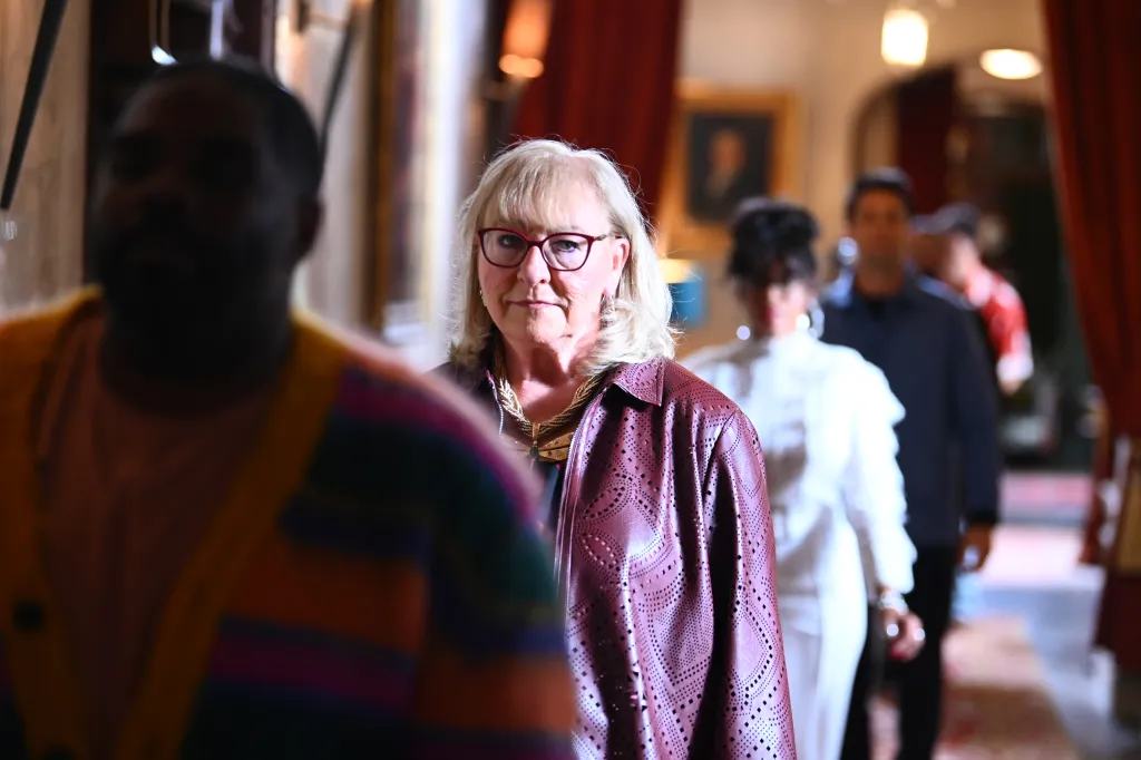 Donna Kelce looks at the camera while walking in a line of people indoors.