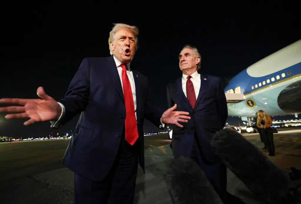President Trump speaking to the media alongside Secretary of the Interior Doug Burgum in front of Air Force One at night.