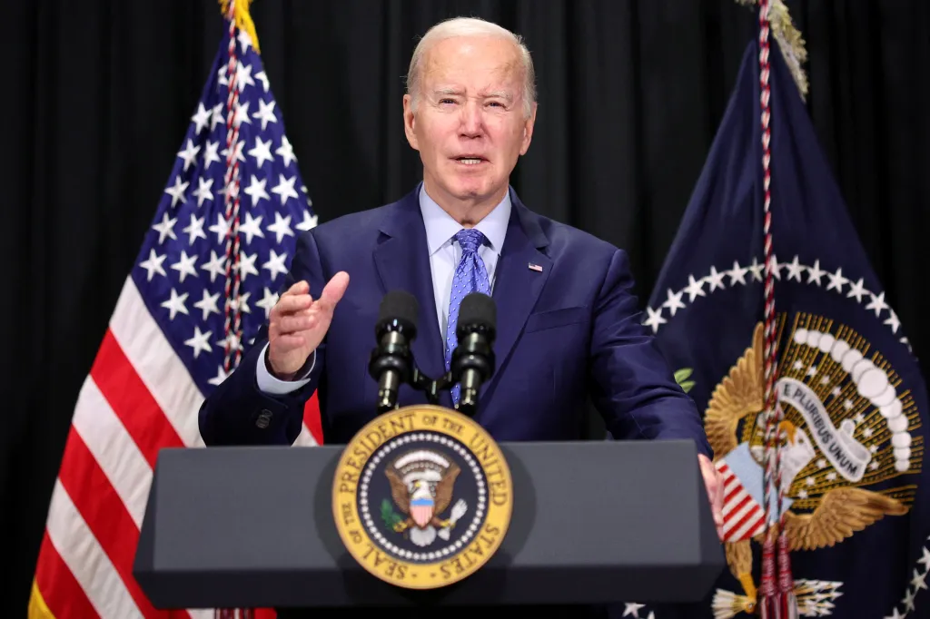 President Joe Biden speaks at a podium with the Seal of the President of the United States, flanked by American flags.