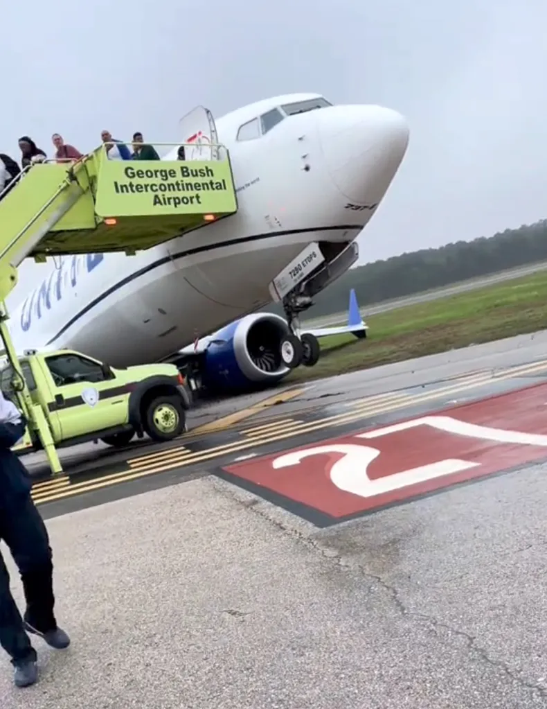 A United Airlines plane tilting on grass after rolling off the runway at George Bush Intercontinental Airport, with passengers disembarking via stairs.