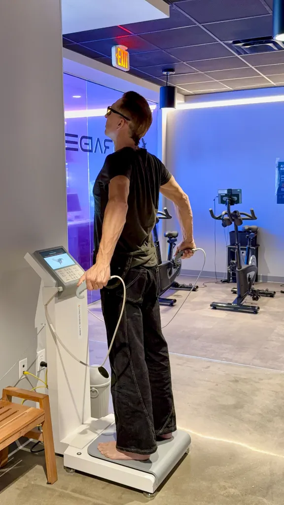 A person standing barefoot on a body composition analysis machine at Upgrade Labs in Austin, Texas.